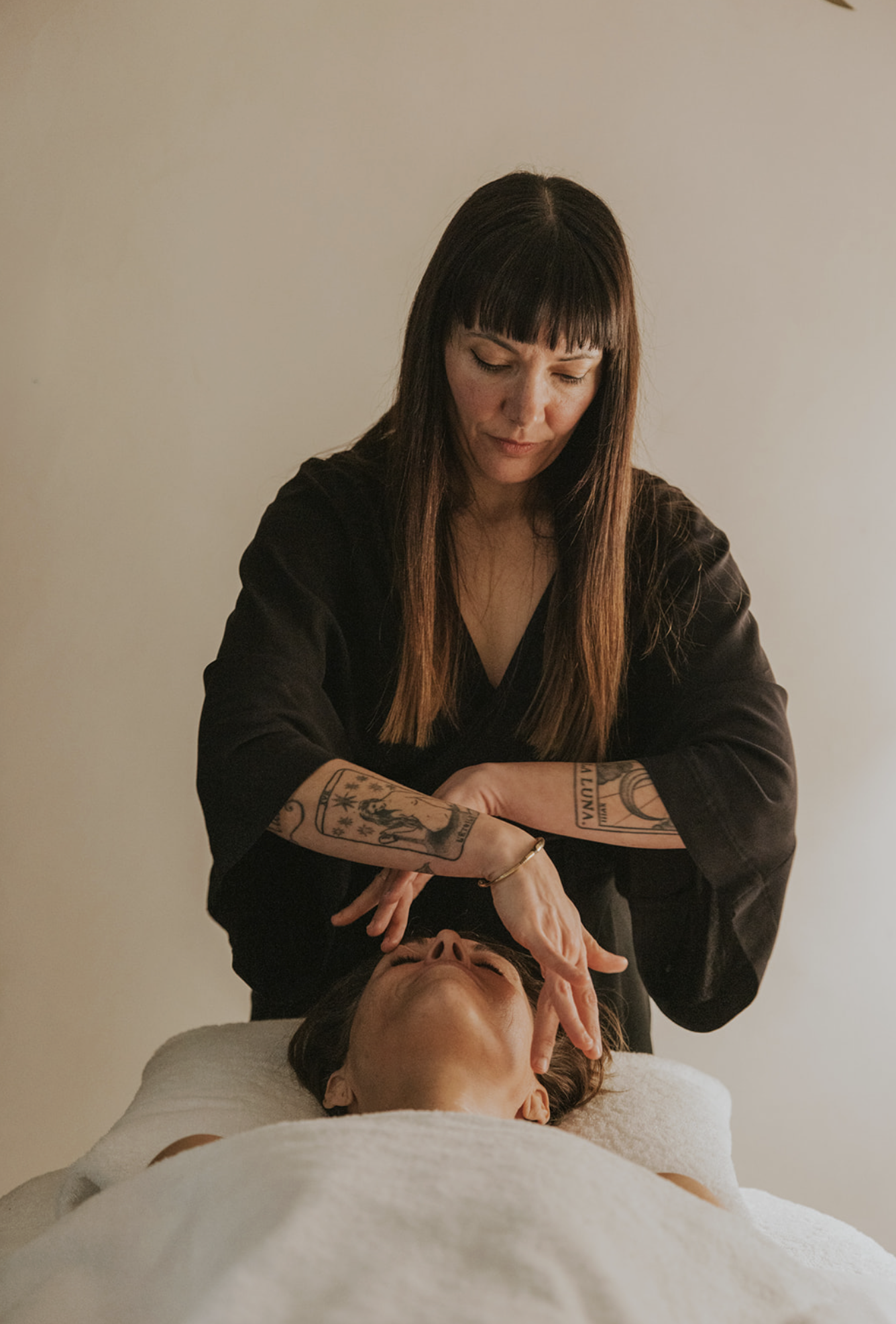 A woman giving a facial treatment to another woman lying on a massage table