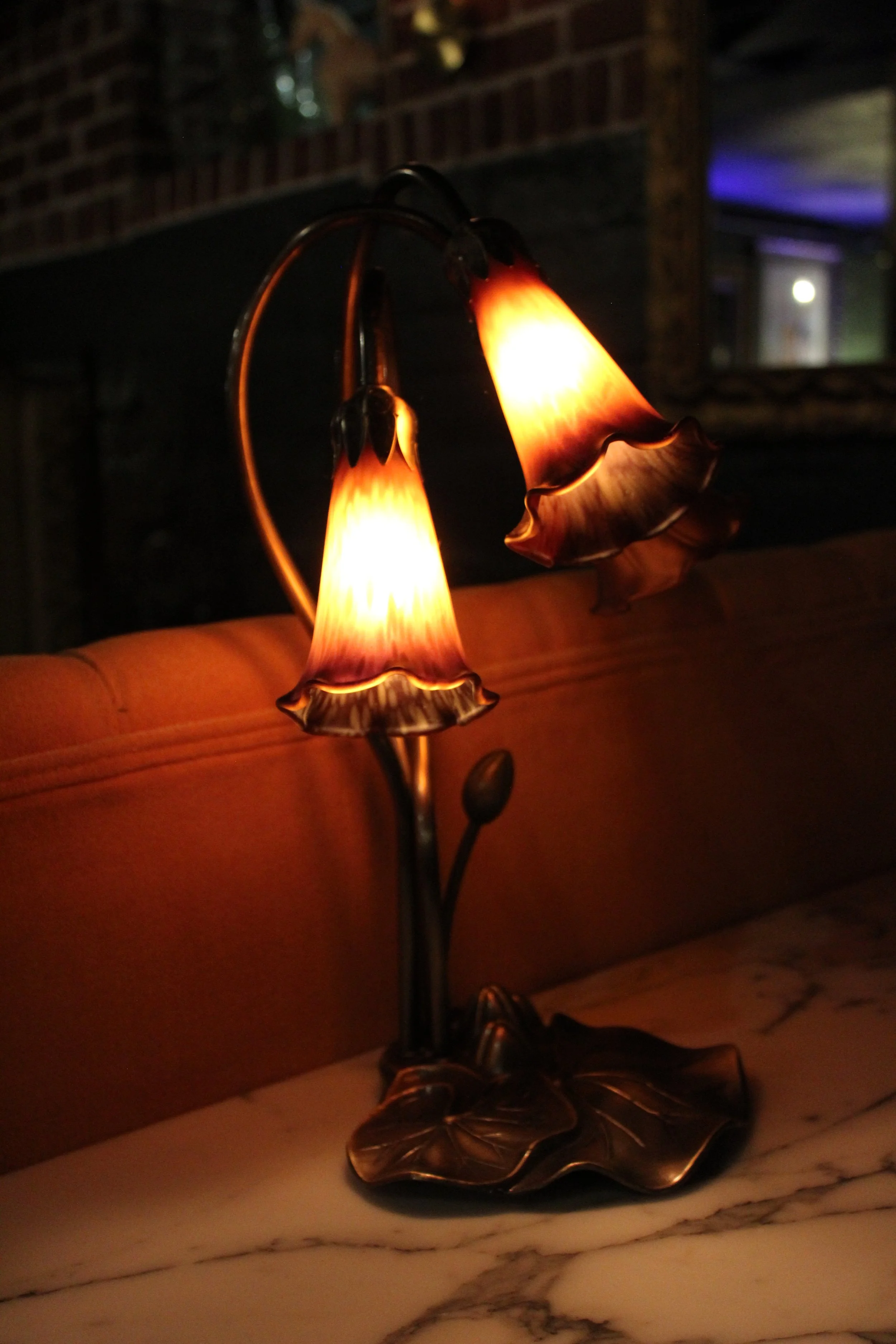 A decorative table lamp with rose-shaped lampshades emitting a warm glow, situated on a marble surface.