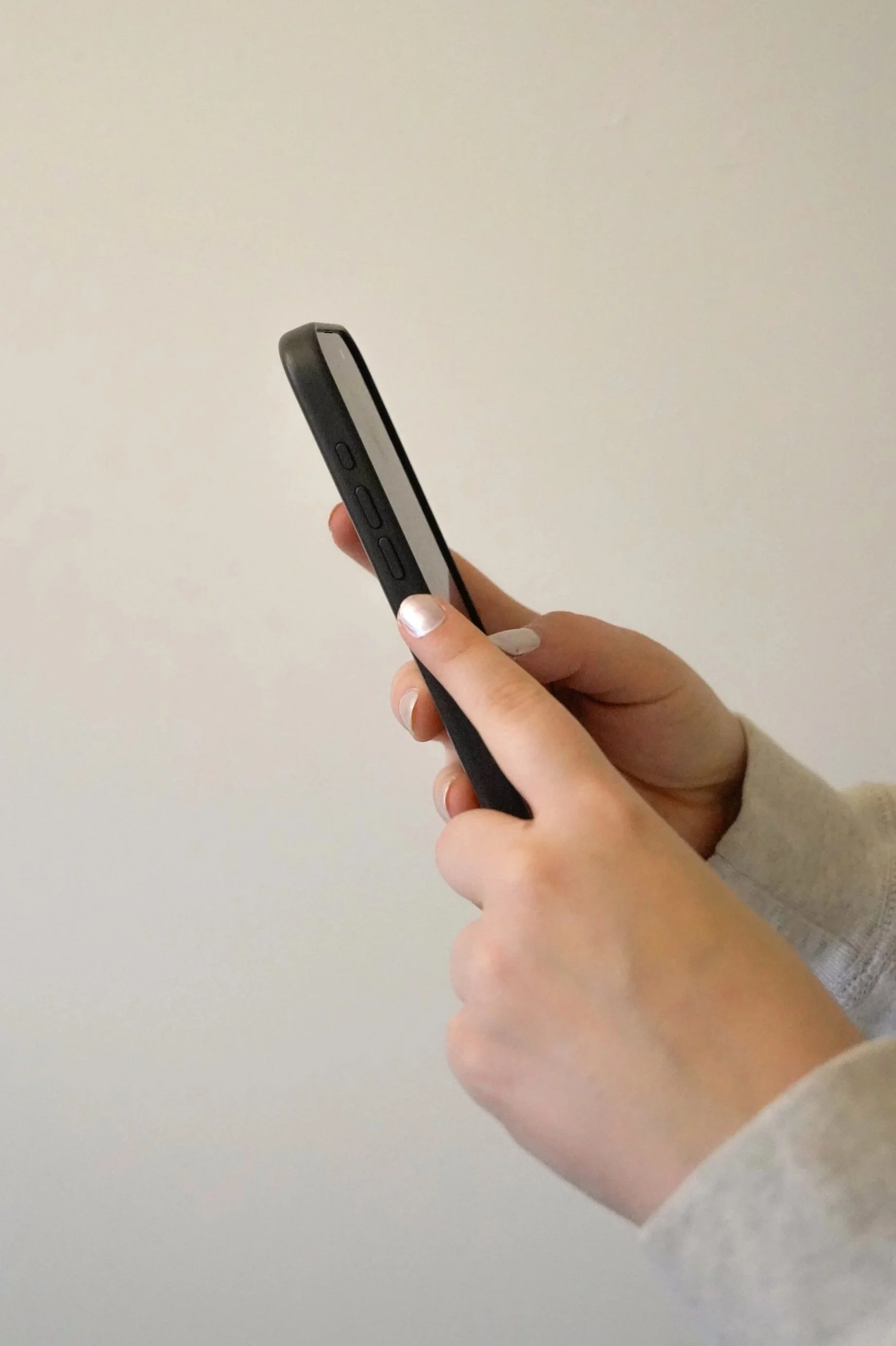 Person holding a smartphone in portrait orientation against a plain background.
