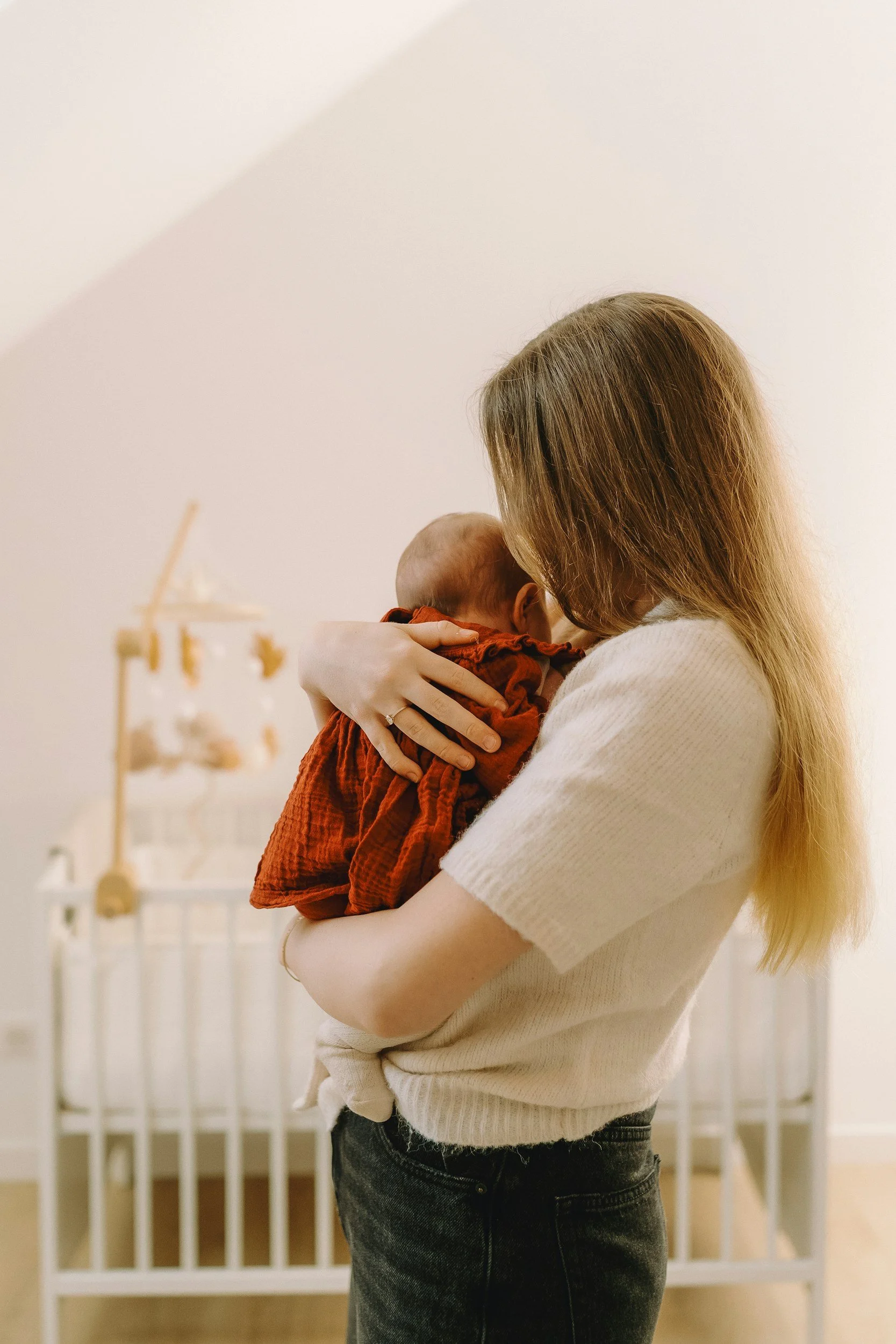 Caregiver holding an infant in a nursery, offering nurturing newborn care and trusted family support for Main Line and Chester County families.