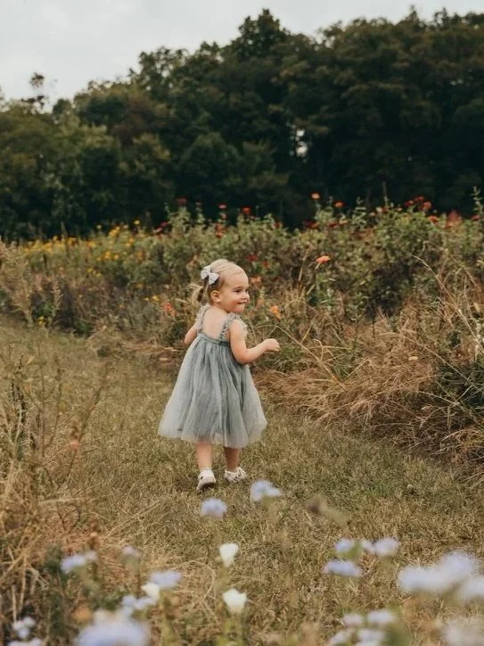 Young girl exploring nature and enjoying outdoor play in a meadow, supporting confidence, independence, and healthy development for Main Line families.