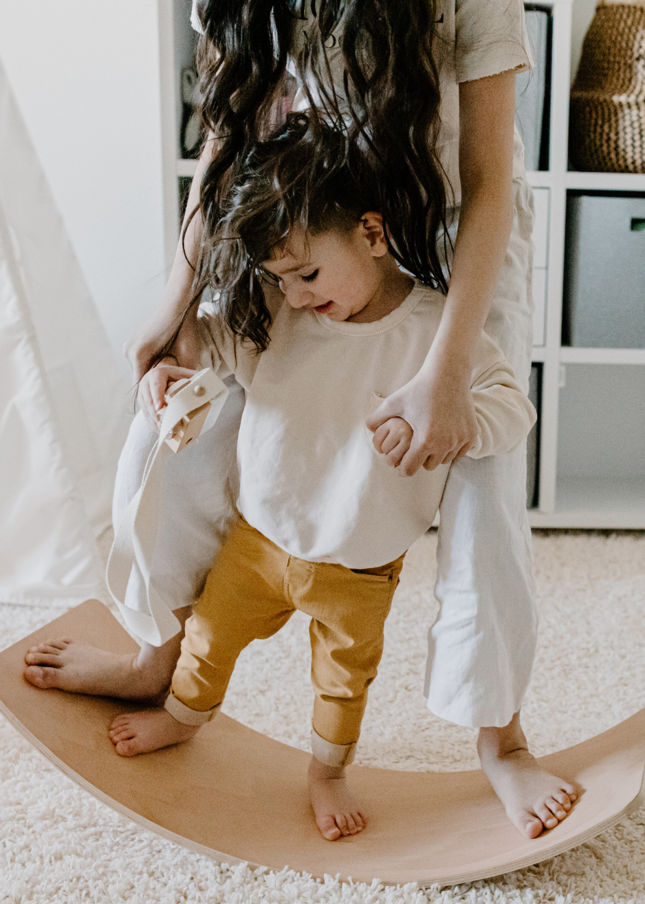 Childcare professional helping a young child develop balance, coordination, and confidence through guided movement and age-appropriate play activities.