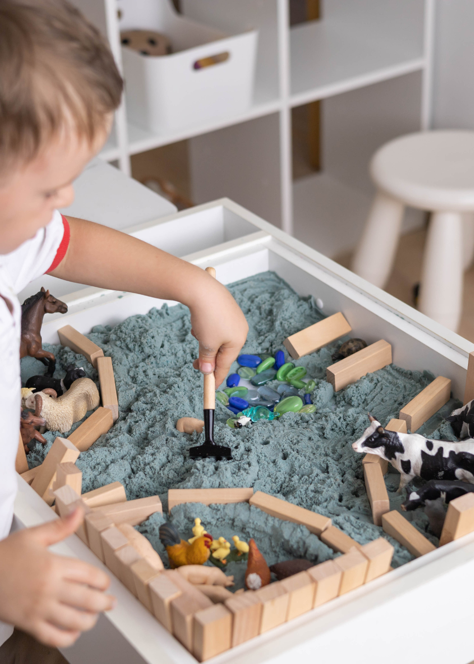 Child engaged in sensory play with toy animals and creative materials, building imagination and developmental skills through hands-on learning in Chester County, PA.