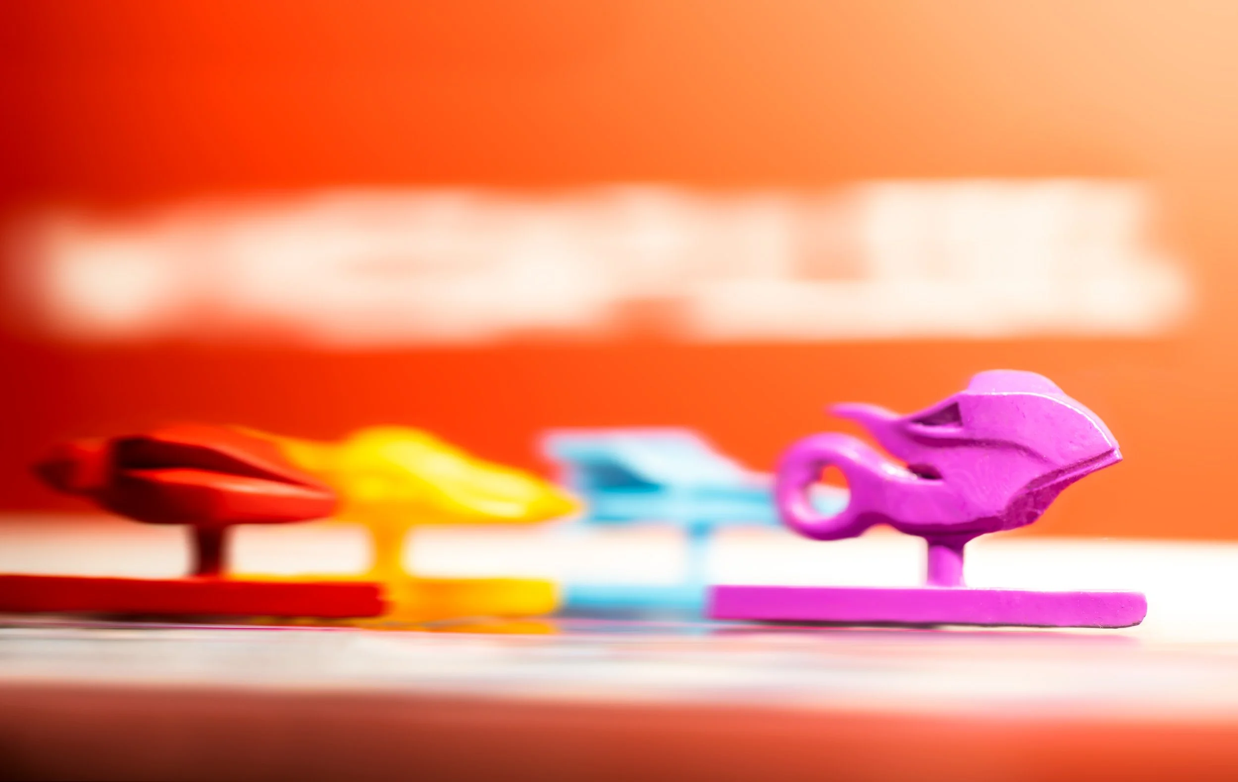 Colorful hover crafts, racing across a surface with an orange background.