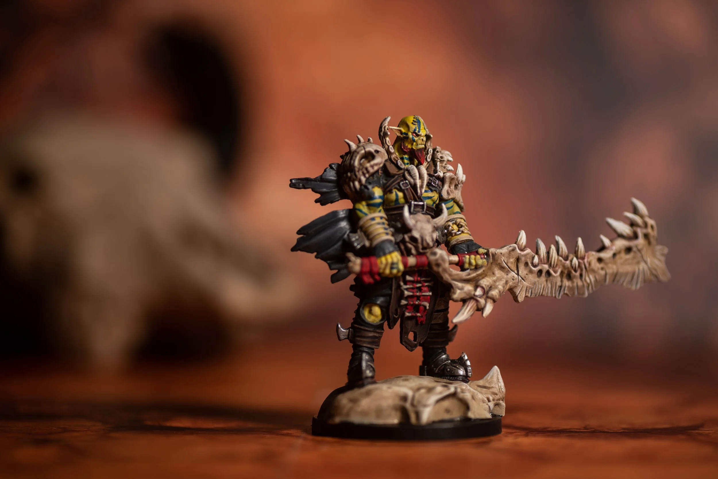 A painted miniature figure of a fantasy warrior holding a large, bone-like sword, standing on a rocky base.