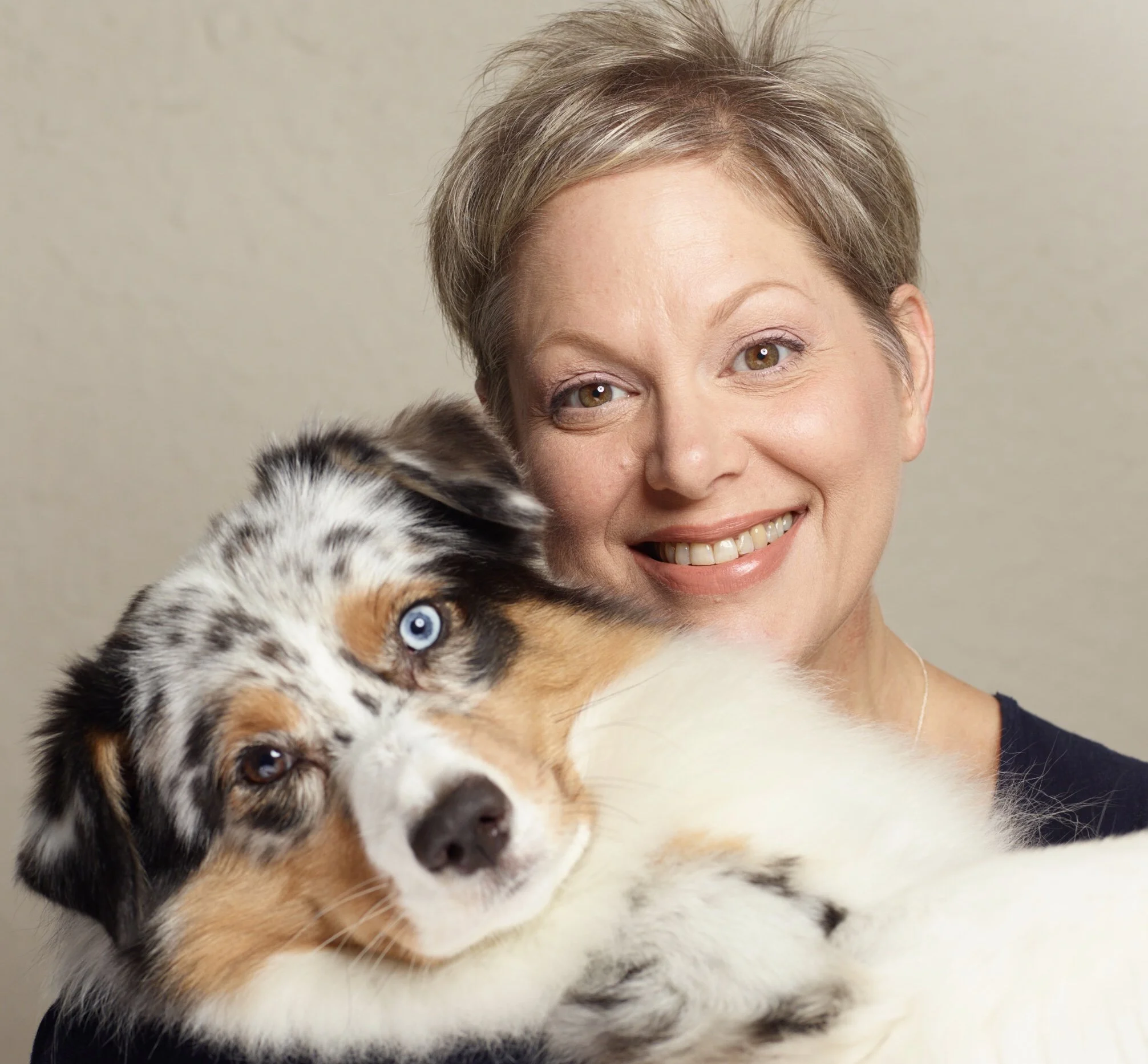 Nikki Marenbach holding an Australian Shepherd puppy with blue eyes. Wyndcrest Aussies.