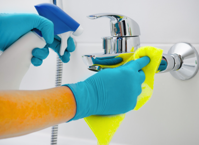 Gloved hands cleaning a bathroom faucet for a polished, sanitized finish as part of professional residential cleaning services.