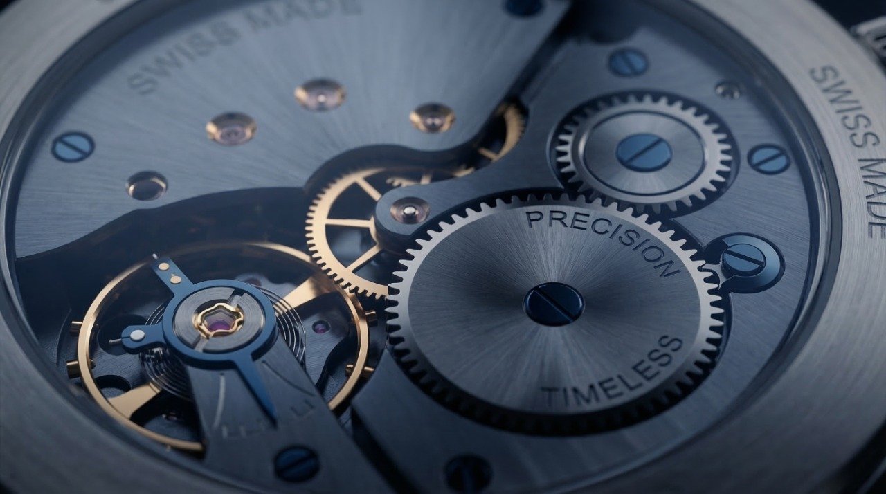 Nahaufnahme des Uhrwerks mit sichtbaren Zahnrädern und Mechanik, Beschriftung "PRECISION", "TIMELESS", "SWISS MADE" auf den Komponenten.
