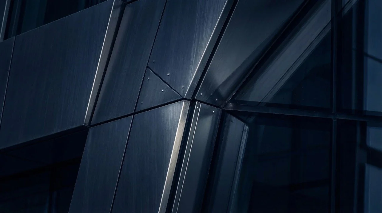 Nahaufnahme einer modernen Gebäudefassade aus dunklem glas und metallischen Oberflächen.