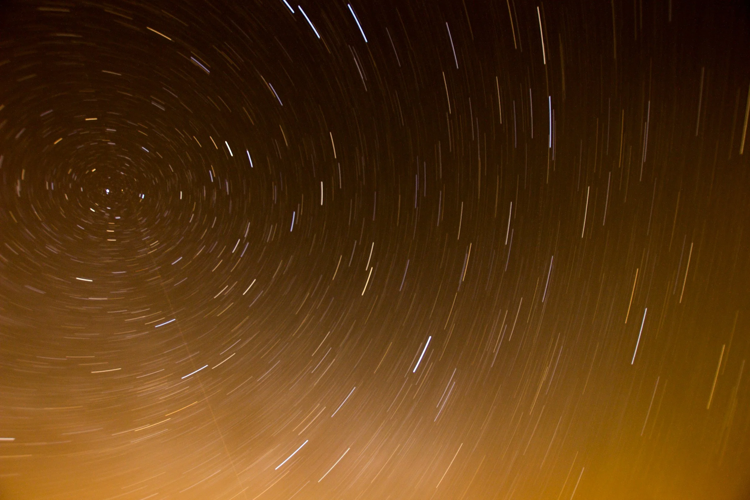 Night sky with star trails forming circular patterns around the Polaris star.