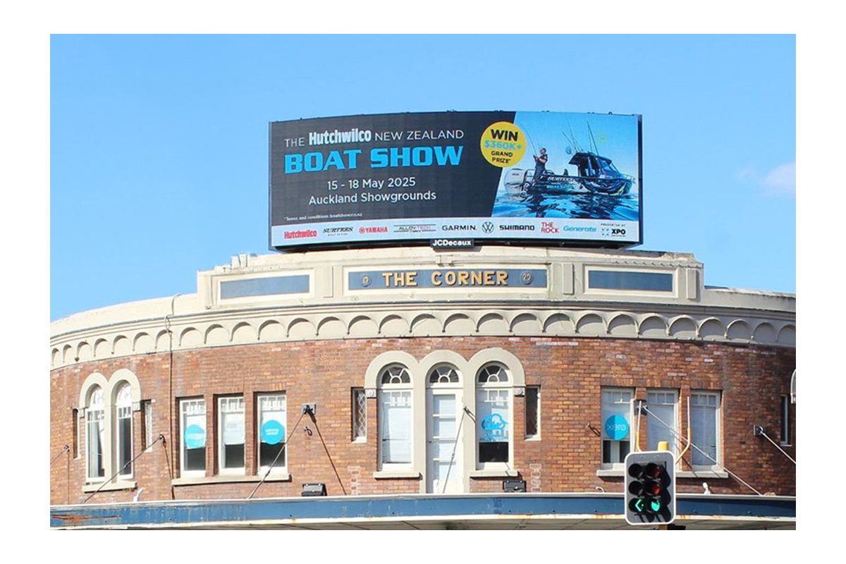 Billboard advertising the 2025 New Zealand Boat Show at Auckland Showgrounds, featuring a boat and a person fishing, with a blue sky background.