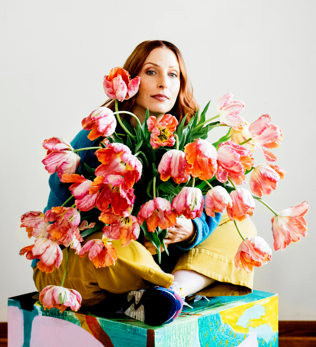 Photo of a white woman with red hair, holding a large bouquet of tulips
