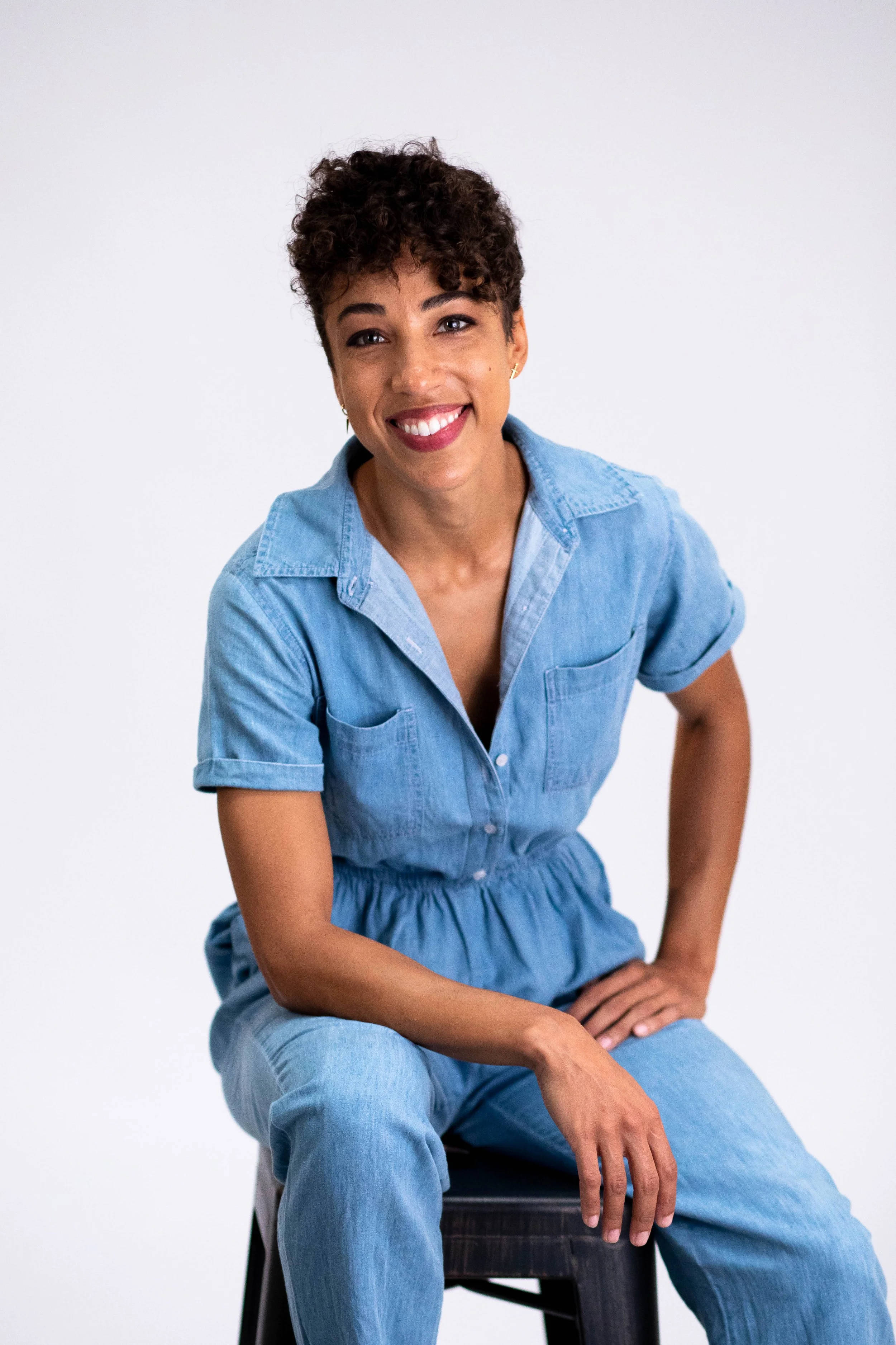 Headshot of a mixed race woman with short, dark brown hair smiling at the camera