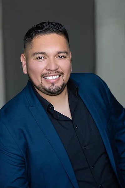 Headshot of a Latino man with short black hair and a goatee