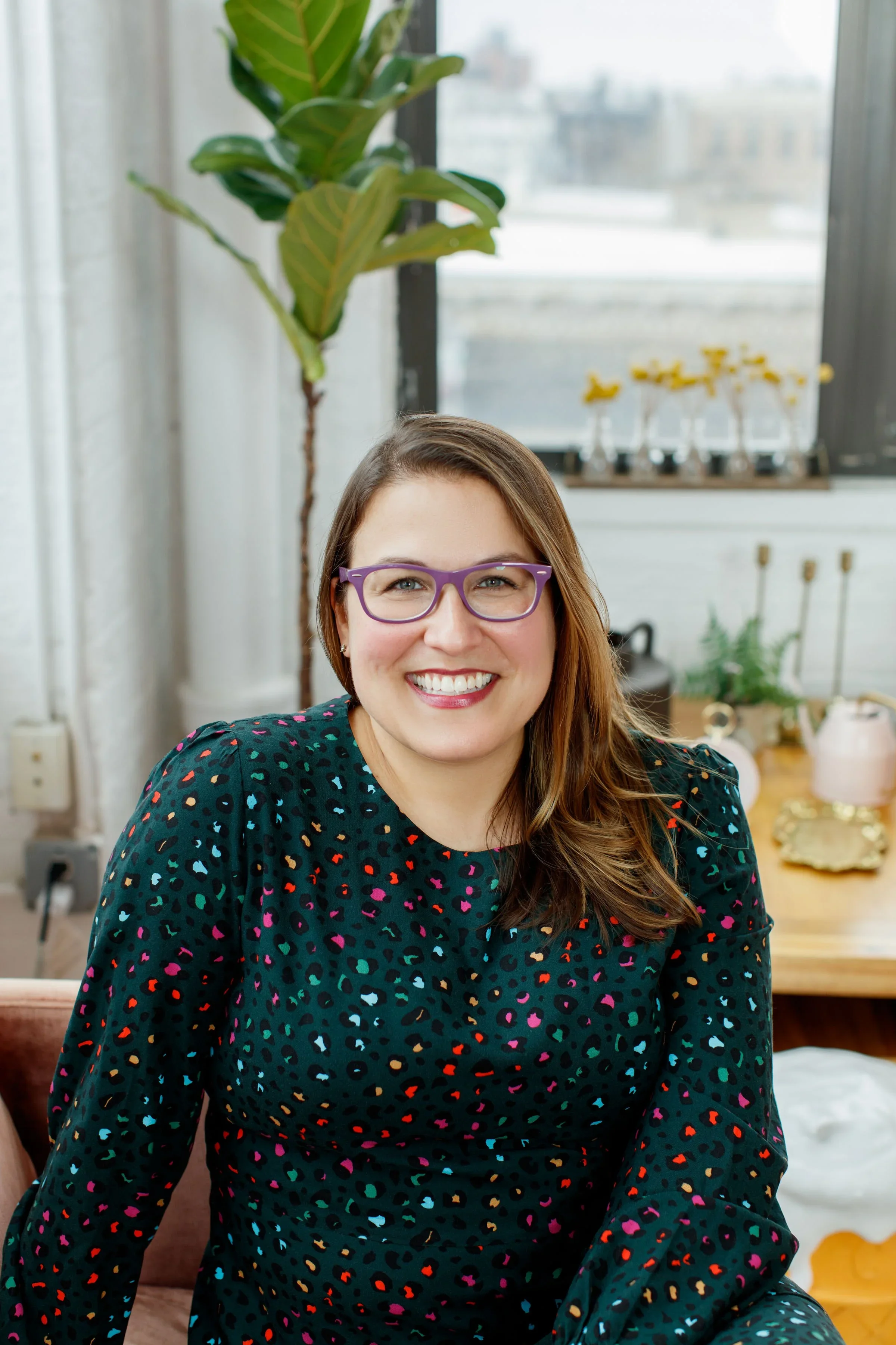 Photo of a white woman with light brown hair, wearing glasses, smiling at the camera