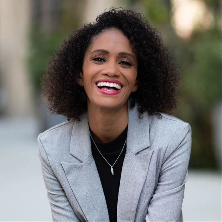 Photo of Crystal, a black woman with curly hair wearing a black top and gray blazer