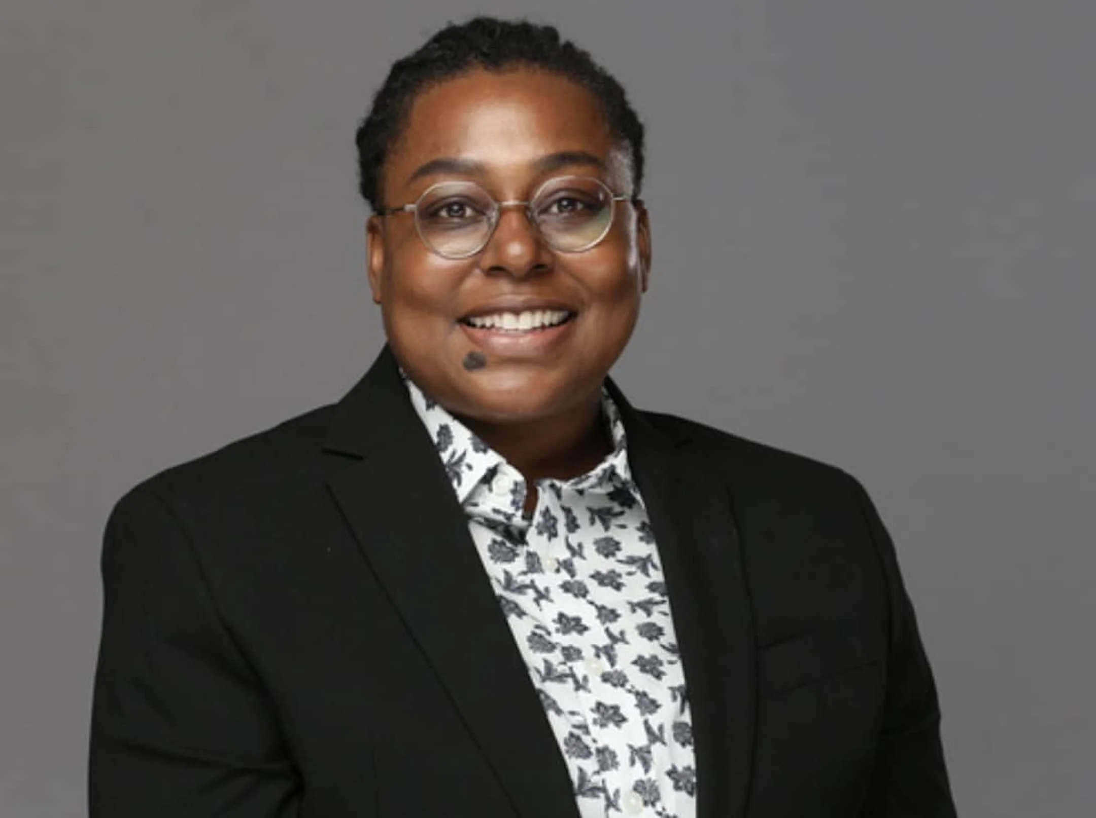 Headshot of a Black woman, wearing glasses, smiling