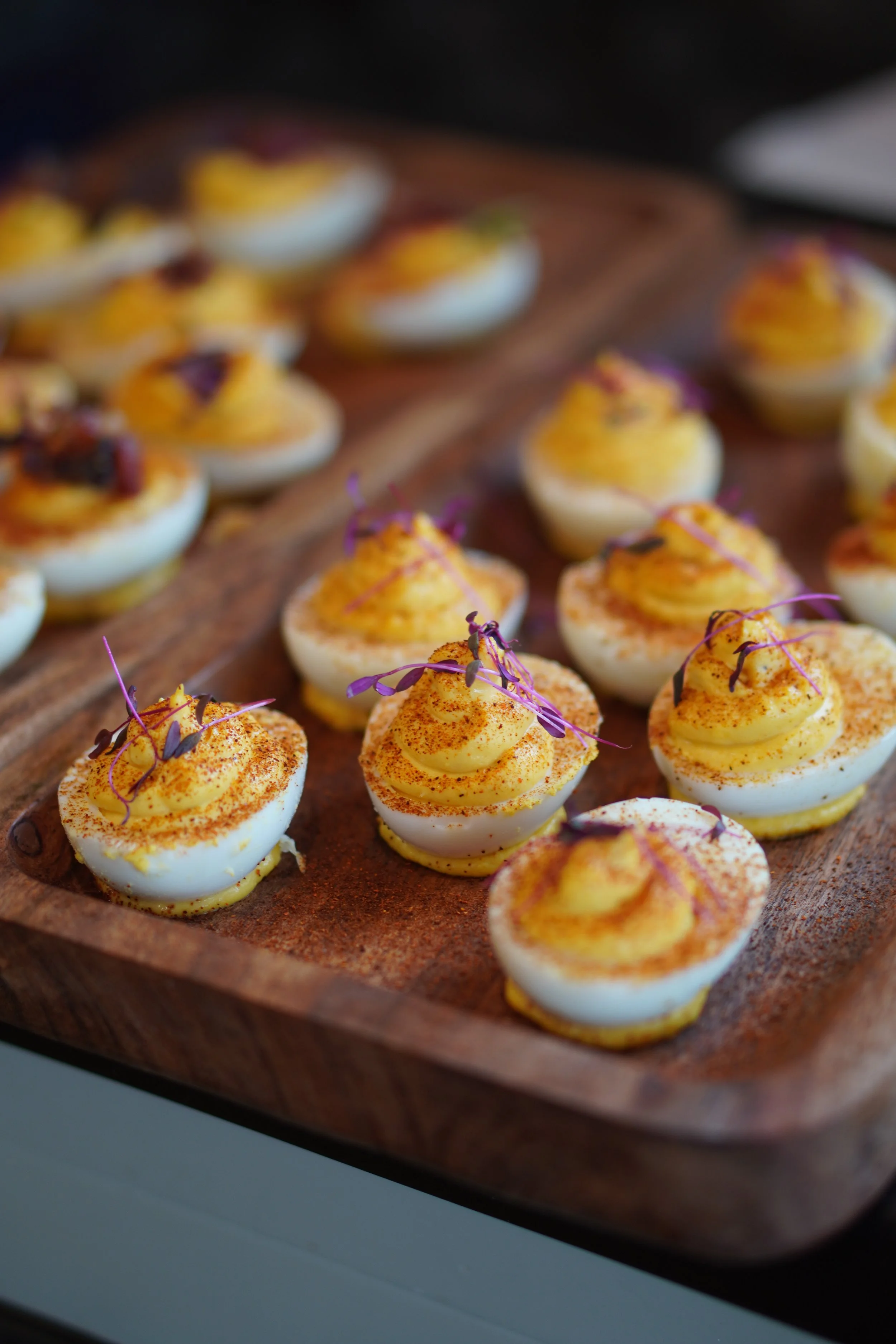 Garnished deviled eggs on a rustic wood board from Tater's Lowcountry Kitchen catering menu, North Charleston SC