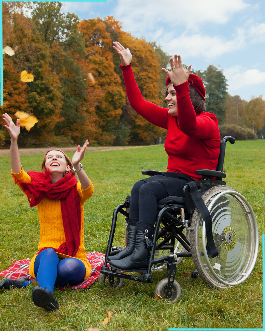 A woman in a red sweater and beret in a wheelchair playing with a girl in a yellow dress and red scarf in a park during fall, throwing leaves in the air and smiling.