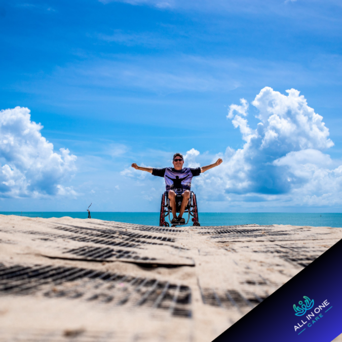 Person in a wheelchair enjoying a beach day with a blue sky and clouds.