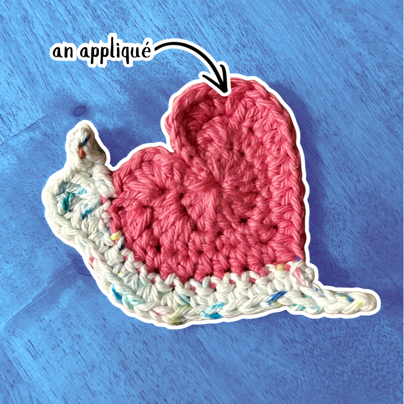 A crocheter appliqué of a snail with a heart-shaped shell