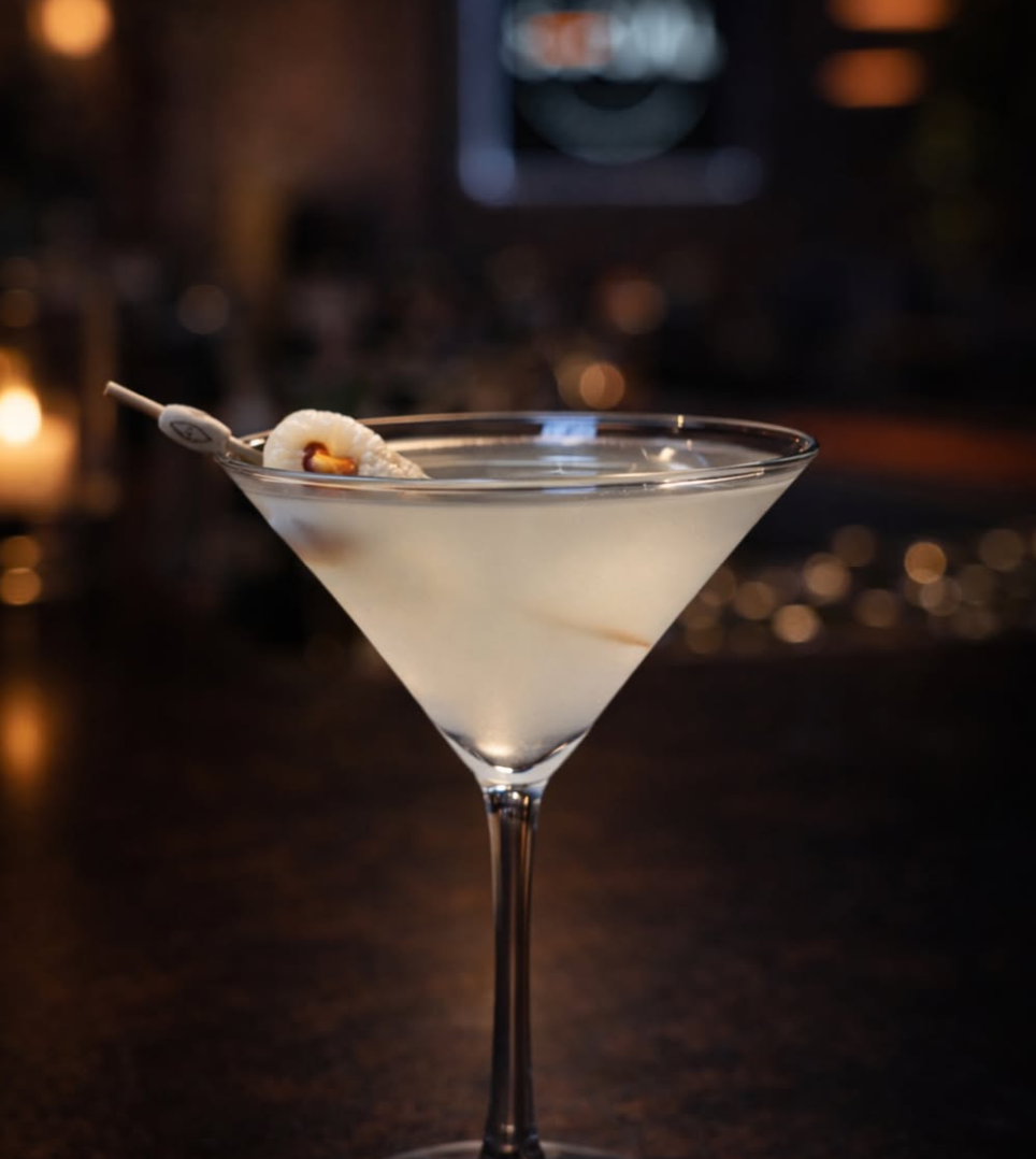A martini cocktail in a classic martini glass garnished with a small piece of lemon peel.