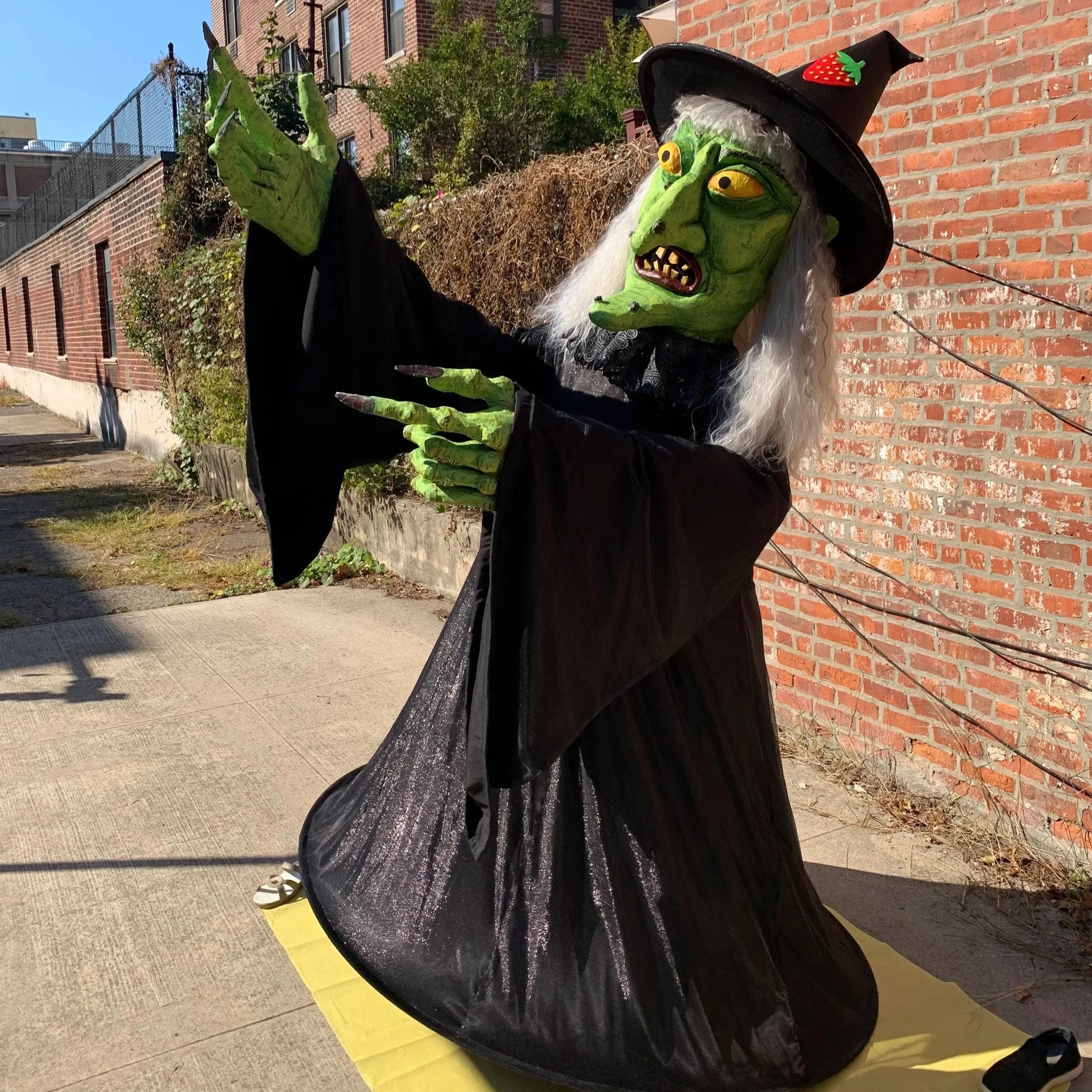 Bread and Puppet style Halloween Witch costume with large, green, papier mache head and hands, 8 foot tall figure in black dress, and pointed hat
