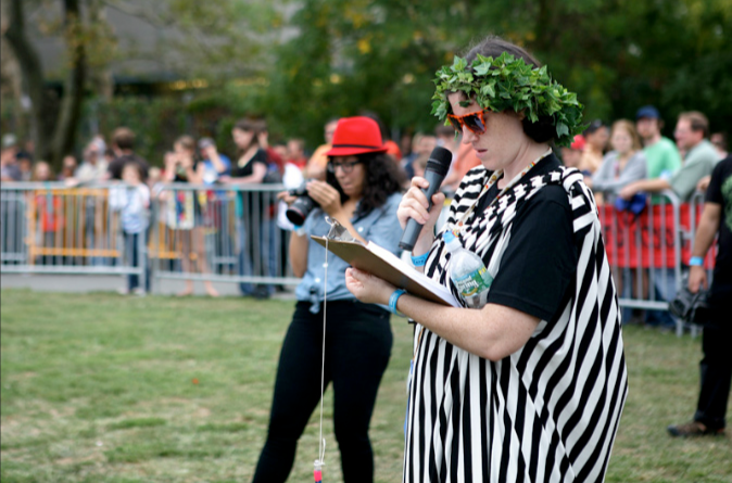 Anney Fresh Ozar dressed in a referee striped toga with clipboard at Chariot Races at World Maker Faire