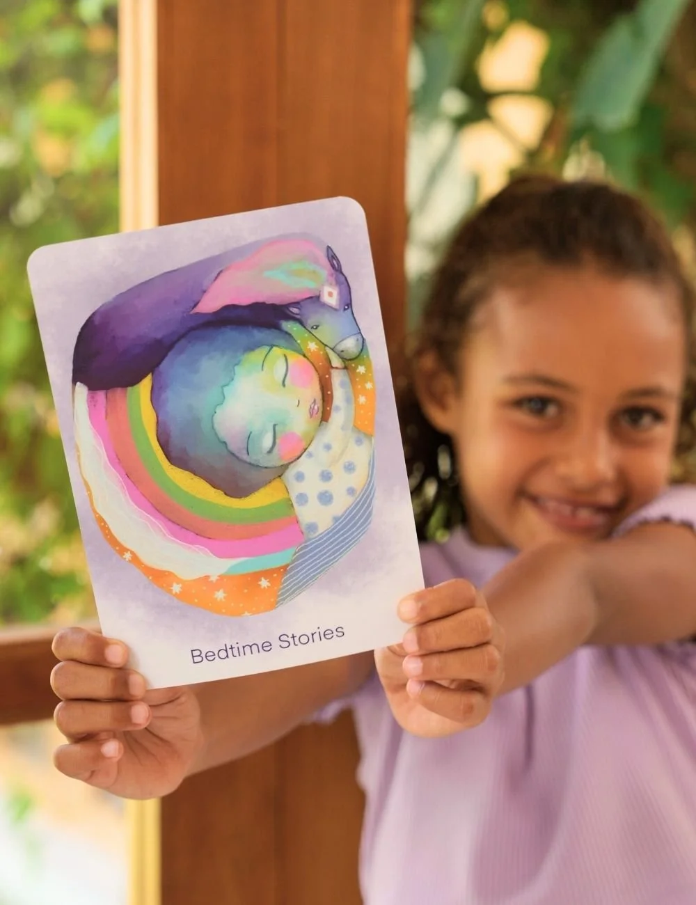 Young girl holding a Little Lightworkers mindfulness card called Bedtime Stories.