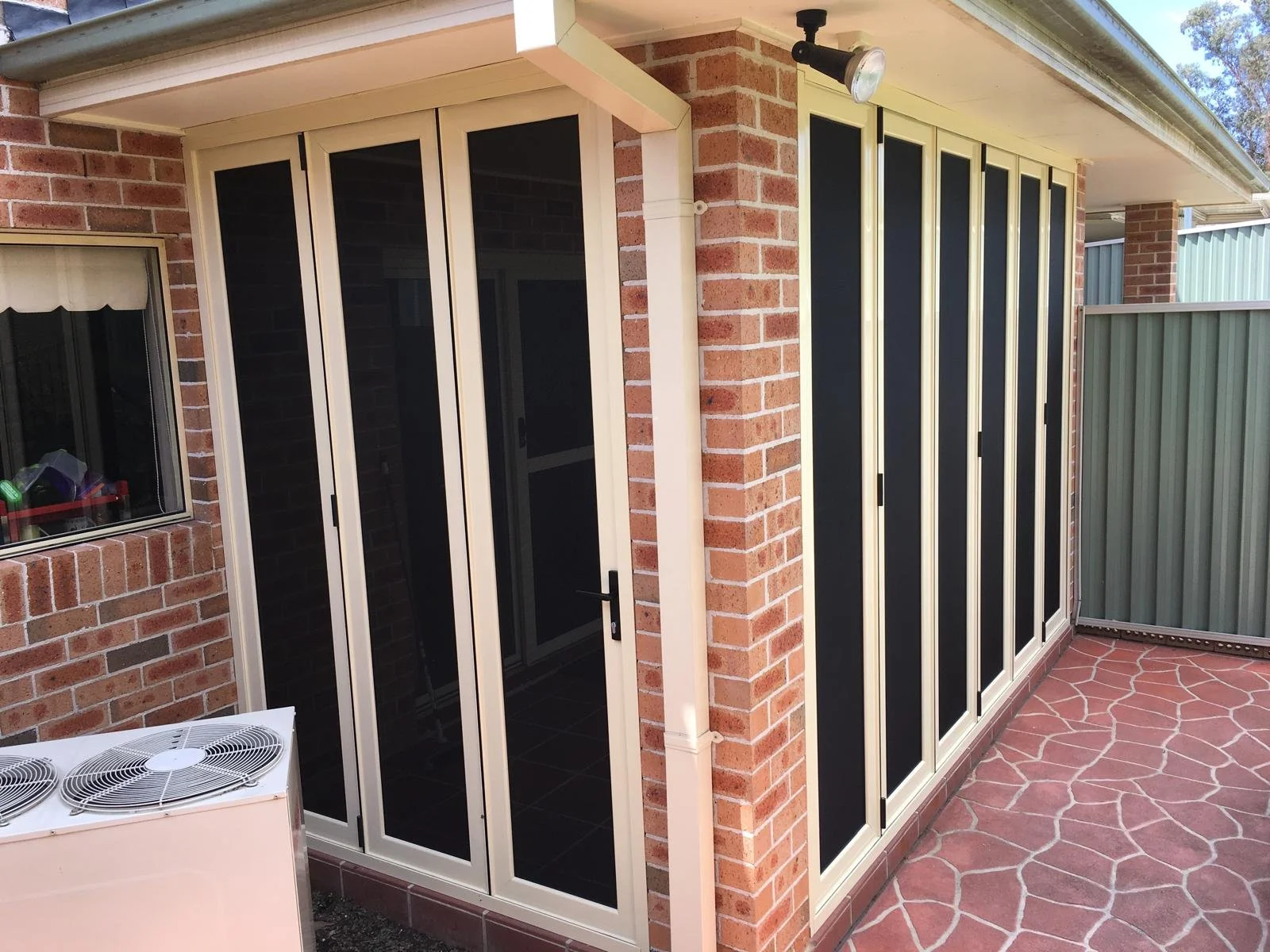Sunroom with sliding glass doors, brick walls, and a paved outdoor patio area.
