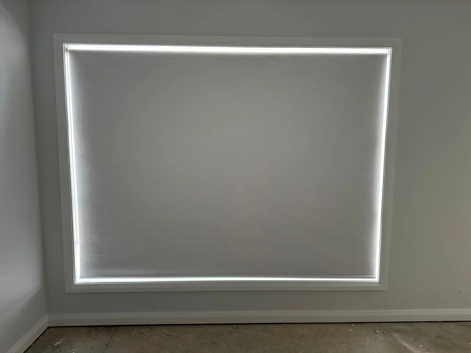 Inside view of a room with a ceiling window installed with a white blind covering the window, allowing minimal light to enter the room.