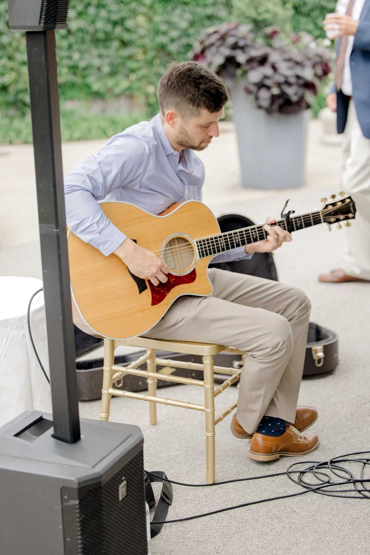 A bride and groom with their foreheads touching, holding a bouquet of white flowers, standing in front of wooden doors surrounded by green ivy and foliage, sharing an intimate moment.