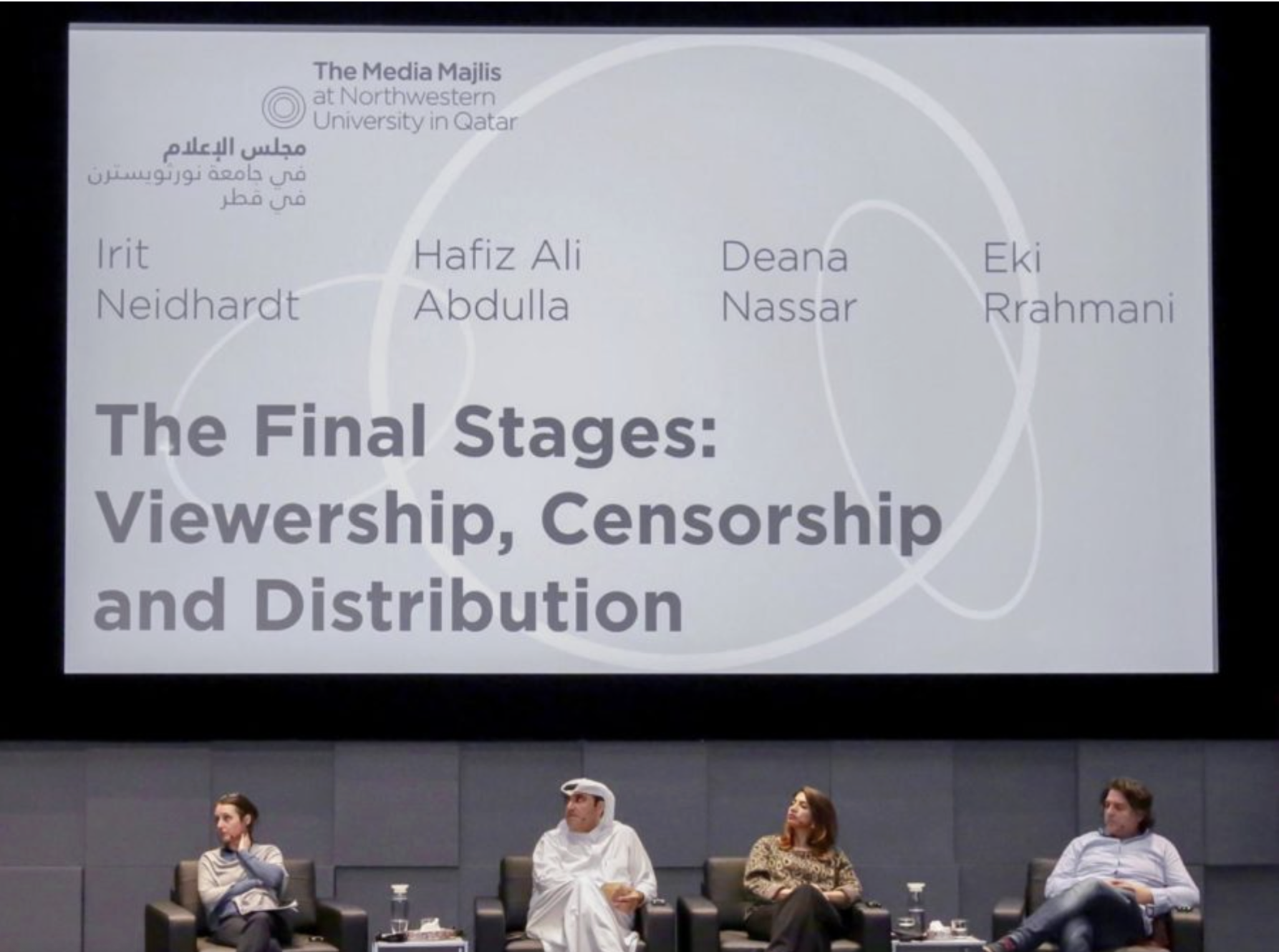 Panel of four people seated on stage beneath a large screen displaying a presentation slide titled 'The Final Stages: Viewership, Censorship and Distribution' with names and affiliations of the speakers. The panelists include two women and two men, with the woman on the far left wearing a striped top, the man next to her in traditional Middle Eastern attire, the woman next to him in a leopard print top, and the man on the far right in a light blue shirt.