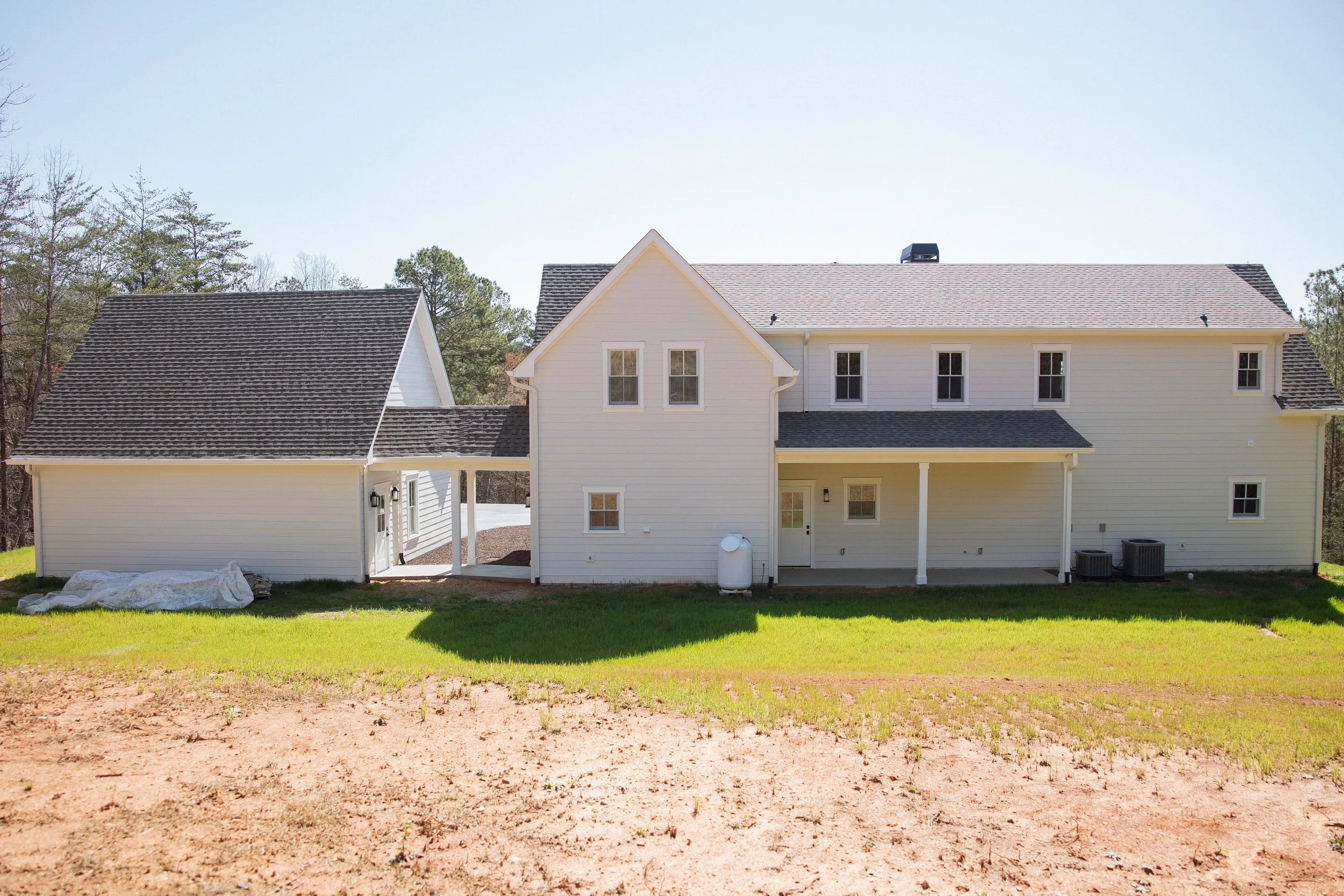 Front view of a two-story, white suburban house with a gabled roof, surrounded by green grass and trees in the background.