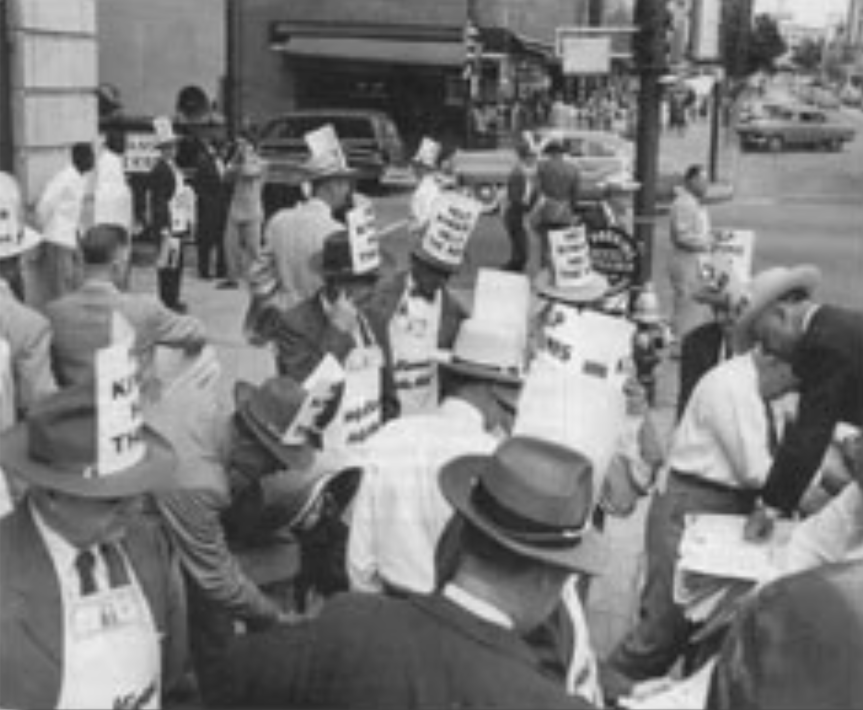 Black and white photo of a protest on a city street with people holding signs that say 'Nix the Tax'.