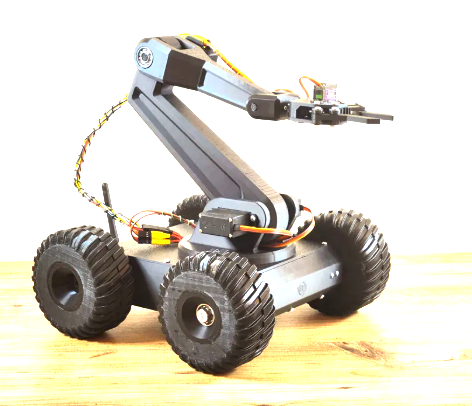 A four-wheeled robot with a robotic arm extending forward, placed on a wooden surface.