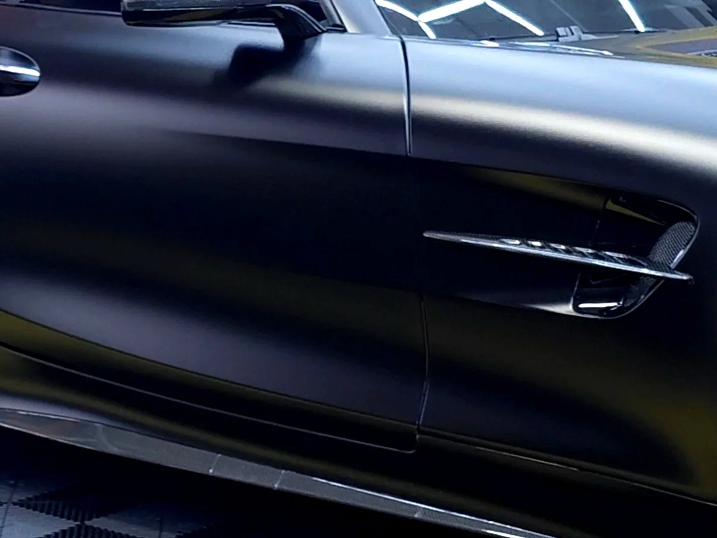 Close-up of a sleek, black sports car with sharp lines and a modern design in an indoor setting.