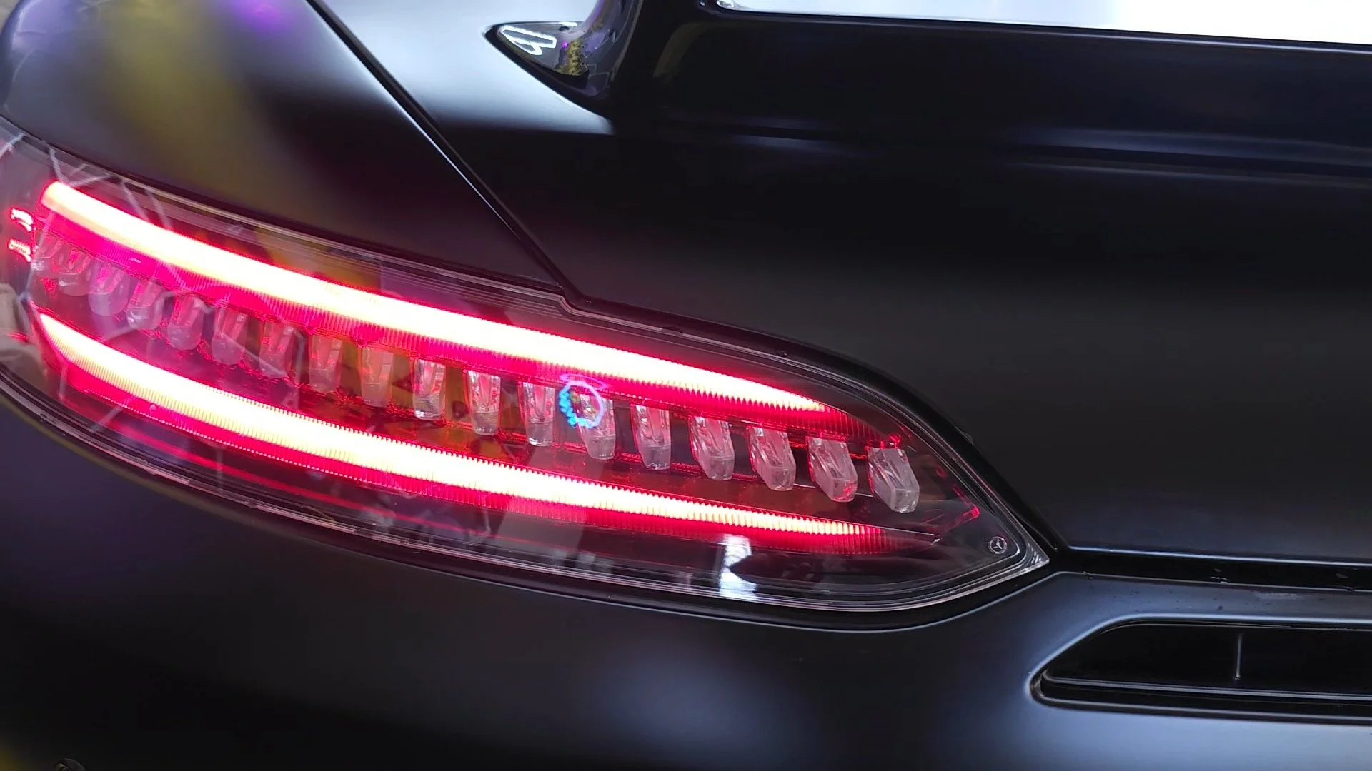 Close-up of a black luxury car's rear left tail light with LED lights illuminated.