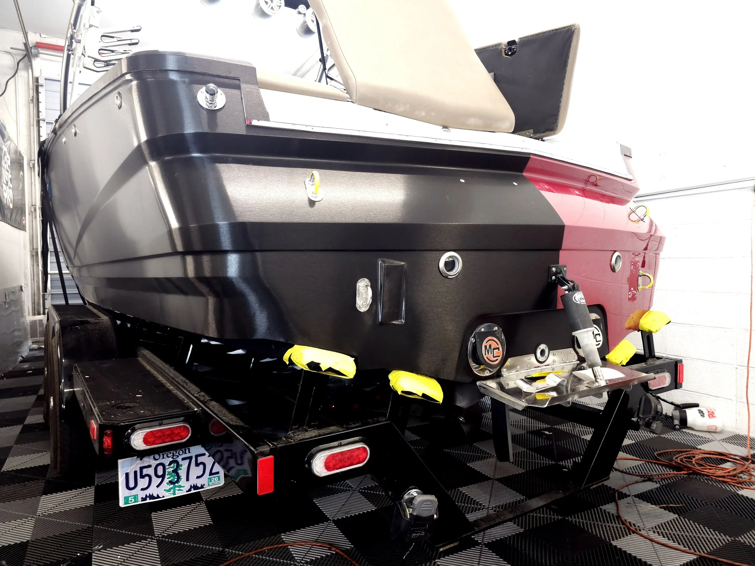 A black and red speedboat on a trailer in a garage or workshop, with tools and equipment visible nearby.