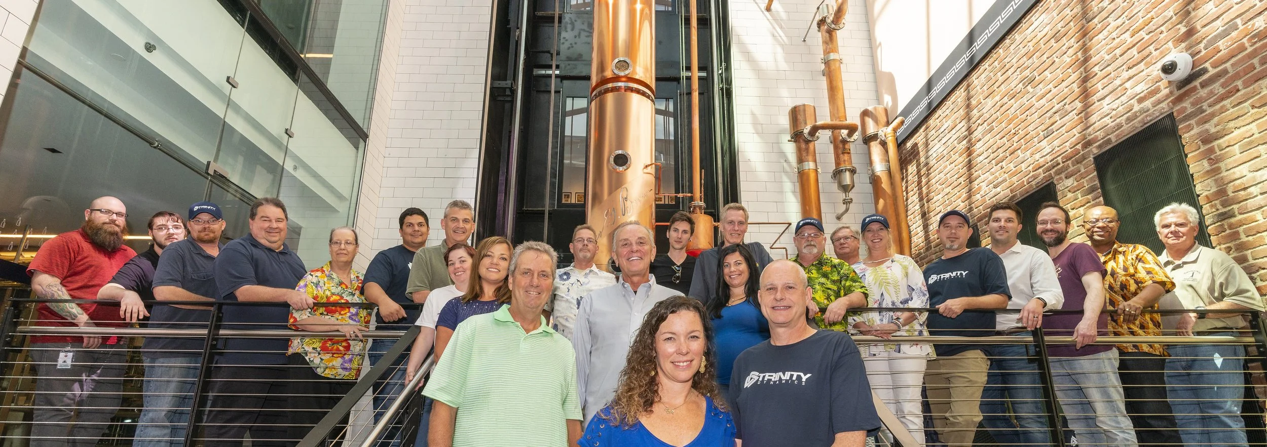 Group of people standing in front of a large industrial copper equipment inside a modern building.
