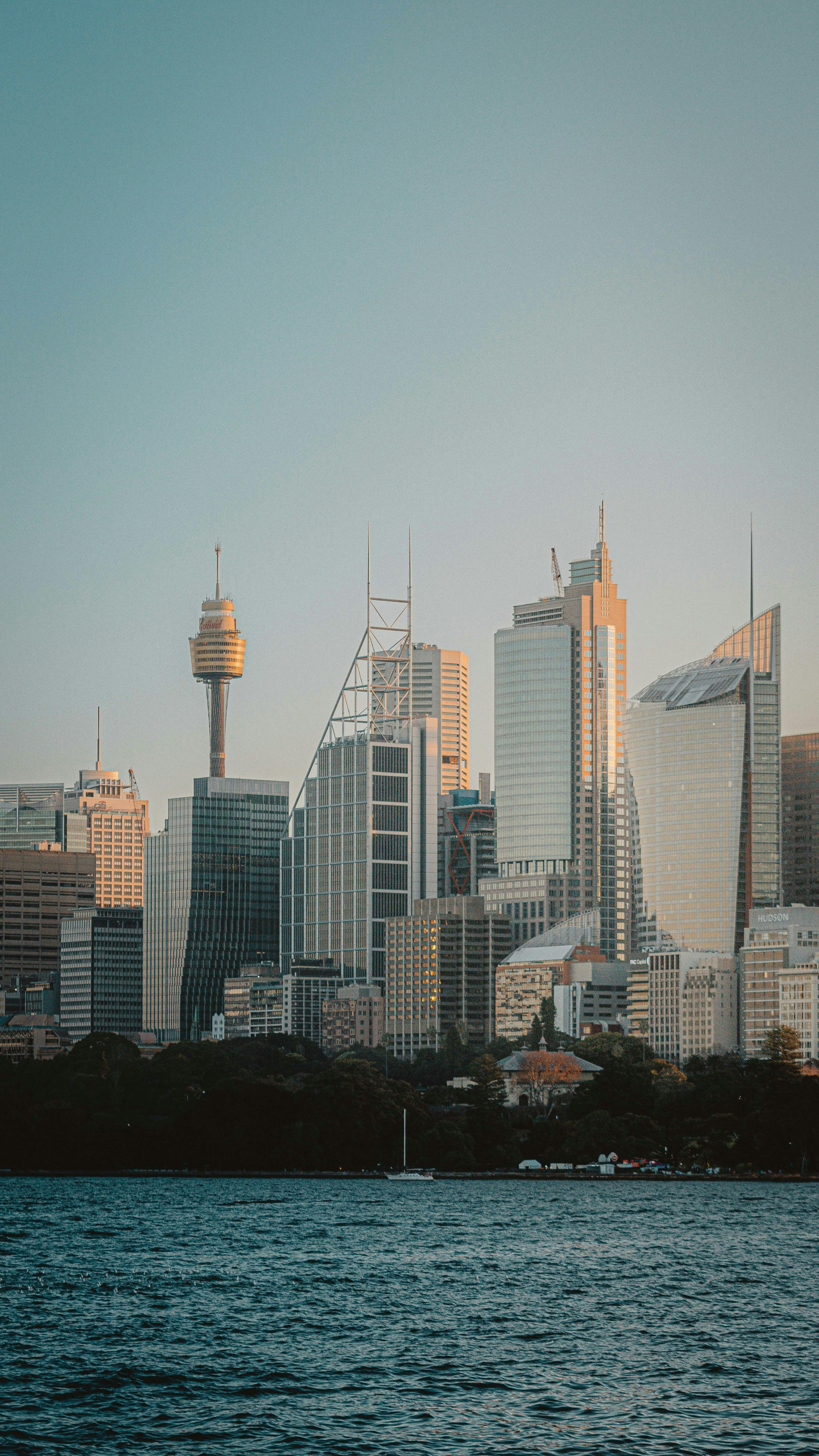 Skyline of a modern city with tall skyscrapers viewed from across a body of water at sunset.