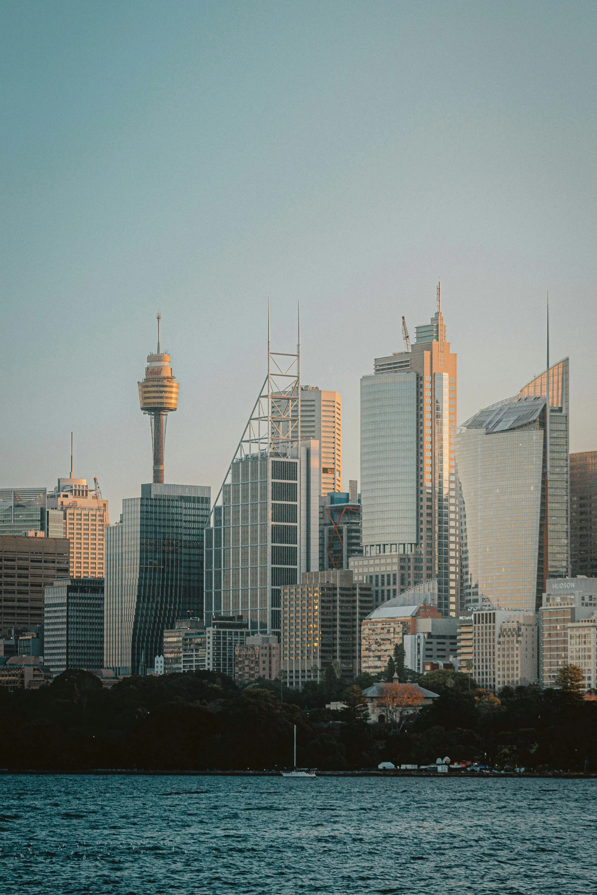 City skyline with skyscrapers and the water in the foreground, under a clear sky.