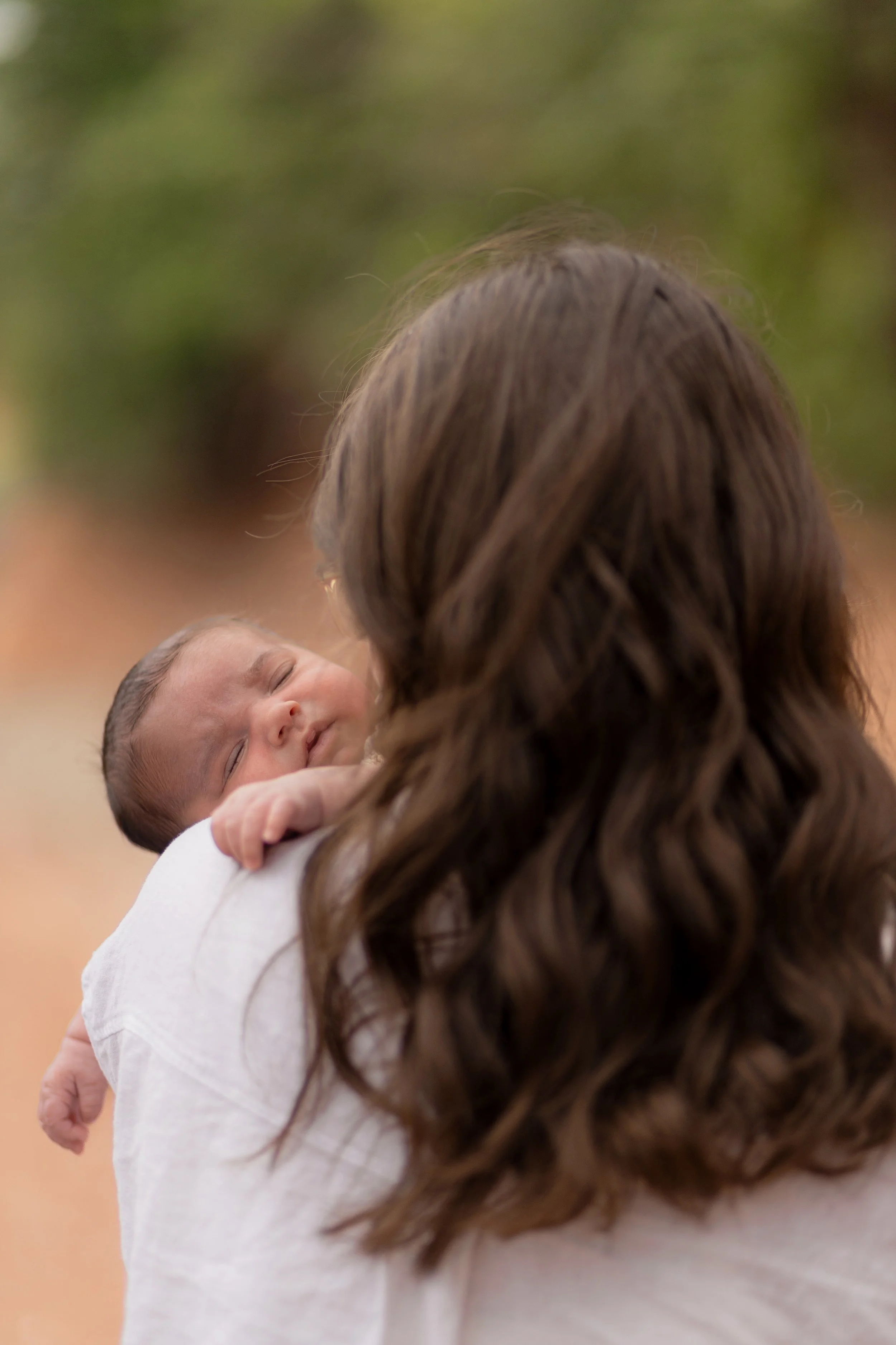 A woman holding a sleeping baby outdoors.
