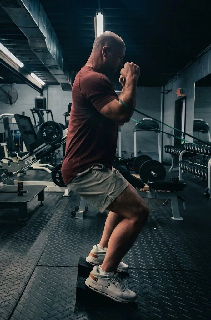 A client squatting with resistance bands around his waist
