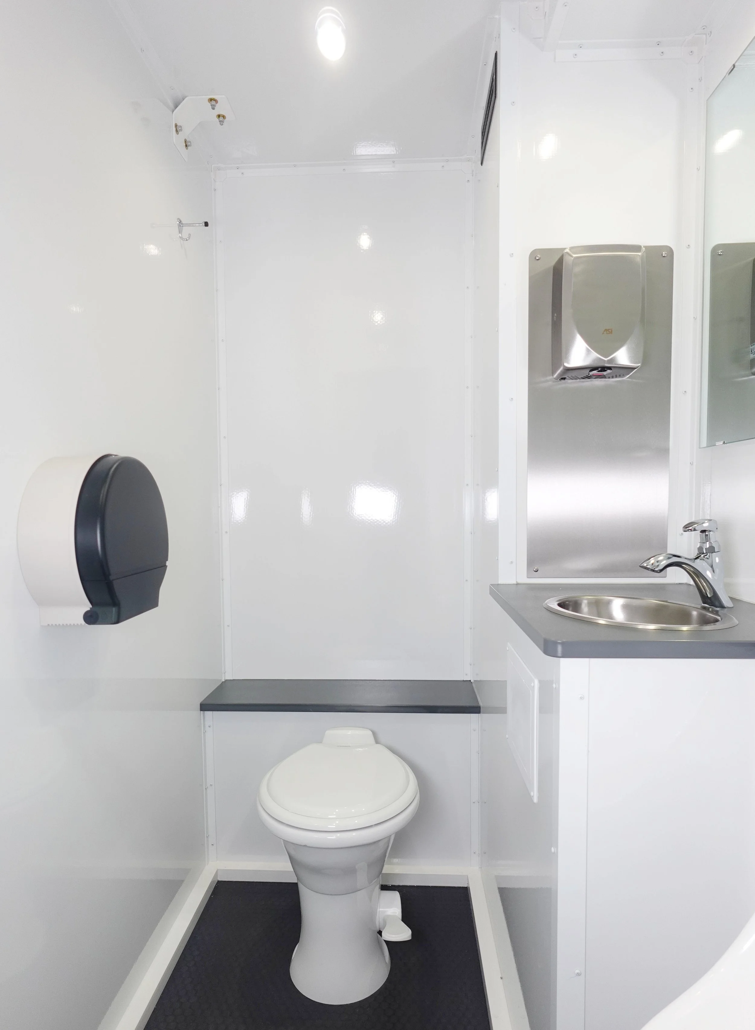 interior of construction restroom trailer with flushing toilet and running water sink