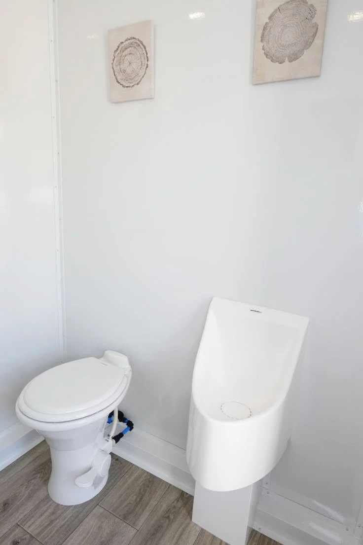 Men's private restroom with toilet and urinal inside a 3-station luxury restroom trailer