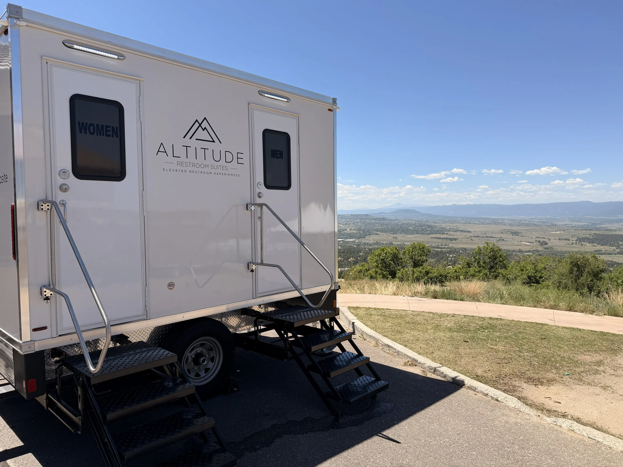 Premium 2-station luxury restroom trailer by Altitude Restroom Suites set up for a Colorado wedding or outdoor event with mountain views in the background.