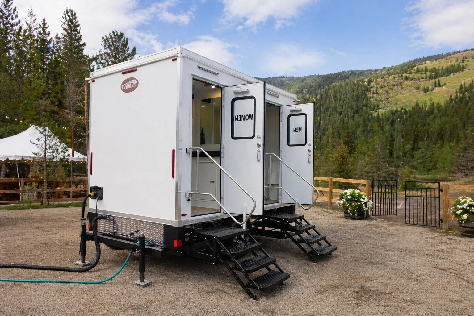 Restroom trailer setup with water hose and power connection in Colorado