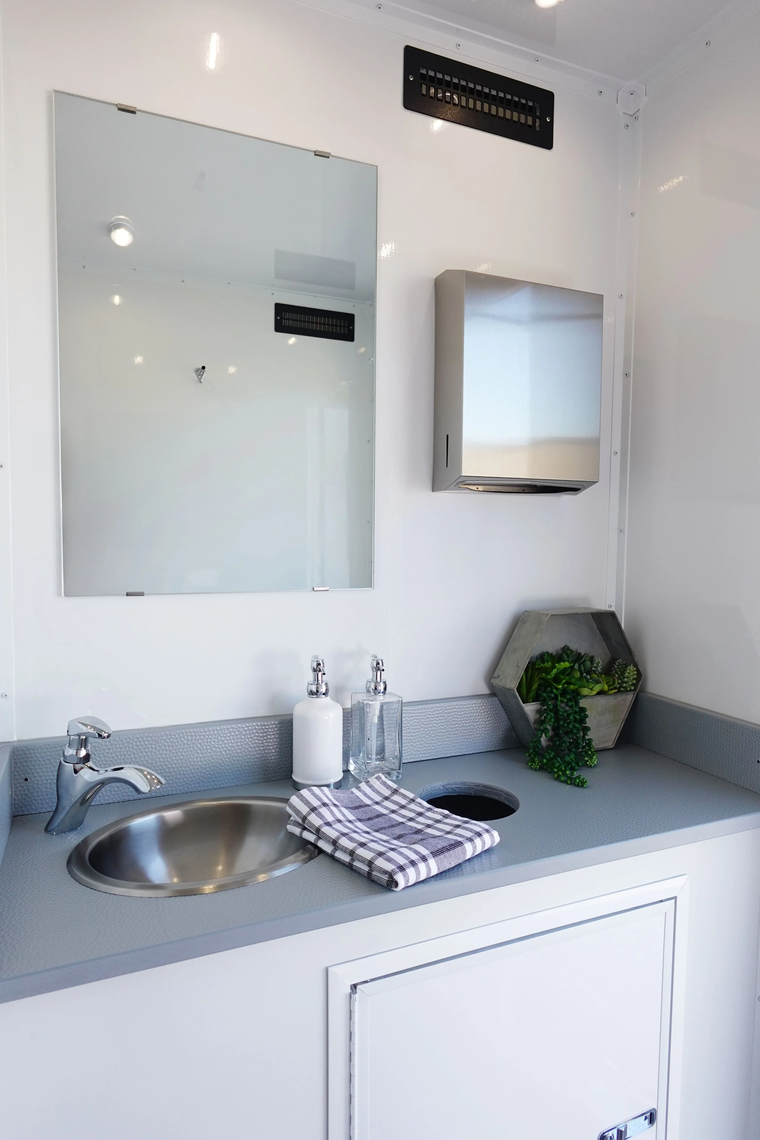 Luxury restroom trailer interior with sink mirror vanity and running water for weddings and events in Colorado