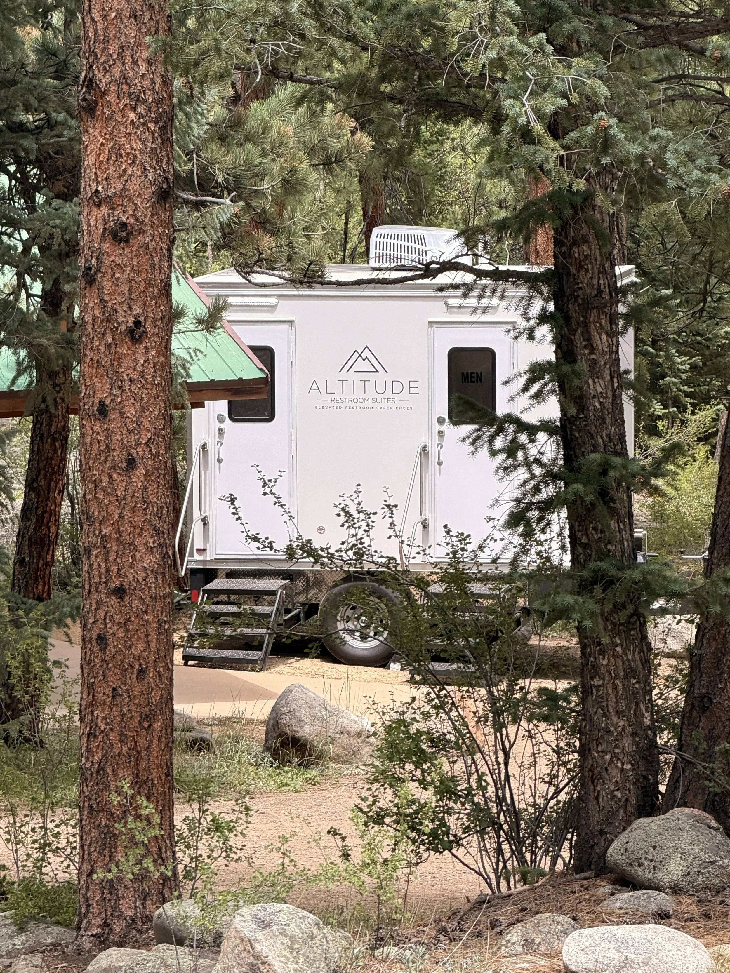 Luxury restroom trailer at a Colorado mountain wedding venue surrounded by pine trees